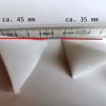 Detailfoto Konzept-Shops. Zwei TetraSnow Schaumstoff-Flocken sind so fotografiert, dass man die Seitenkante der Grundfläche des Tetraeders mithilfe des dahinter liegenden Meterstabes erkennen kann.